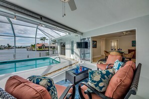 Un amplio espacio exterior con piscina, asientos cómodos y vistas al agua.