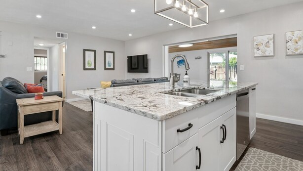 A modern kitchen with a marble countertop, white cabinetry, and a built-in sink.