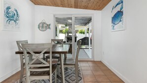 A dining area with a wooden table and chairs, a rug, and a view of an outdoor patio with a grill.