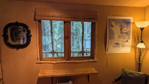 Een kamer met een groot raam, een radiator, een stoel en een poster aan de muur.