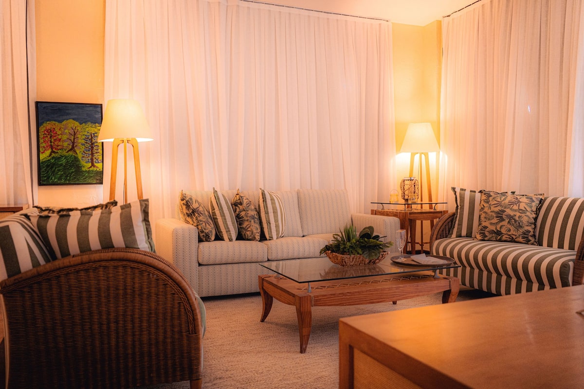 A living room with a sofa, armchairs, a coffee table, and two lamps.
