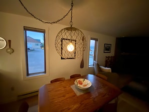 A dining area with a wooden table, a hanging light fixture, and a window with a view of the outside. - Early Season Special! Biking/Hiking trails, garage (Gunnison)