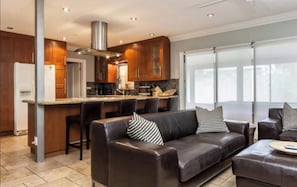 A modern kitchen with dark wood cabinets, a stainless steel range hood, and a bar area with stools. - Charming Pompano Beach escape, nr ocean and hotspots, Walk to Beach, Hot Tub. (Pompano Beach)
