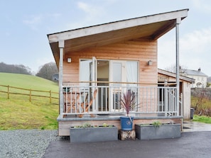 Une cabane en bois avec un balcon, une porte et une fenêtre.
