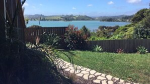 Un patio trasero con un sendero de piedra que conduce a una valla de madera con vista a un lago.