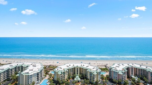 A beachfront hotel with multiple buildings, a swimming pool, and a view of the ocean.