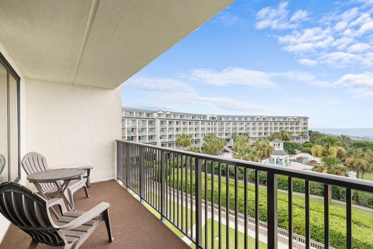 A balcony with a view of a hotel complex and the ocean.