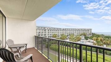 A balcony with a view of a hotel complex and the ocean.