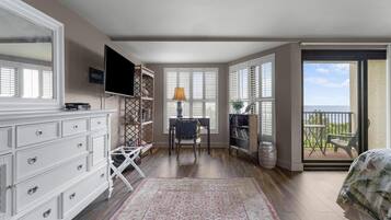 A bedroom with a large window, a TV, a dresser, and a chair.