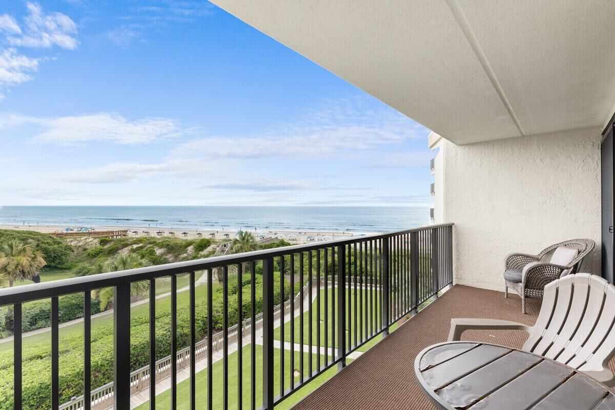 Ein Balkon mit Blick auf den Strand, einem Tisch und zwei Stühlen.