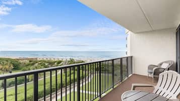 Ein Balkon mit Blick auf den Strand, einem Tisch und zwei Stühlen.