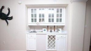 Eine Küche mit weißen Schränken, einem Fenster über der Spüle und einer dekorativen Krabbe an der Wand.