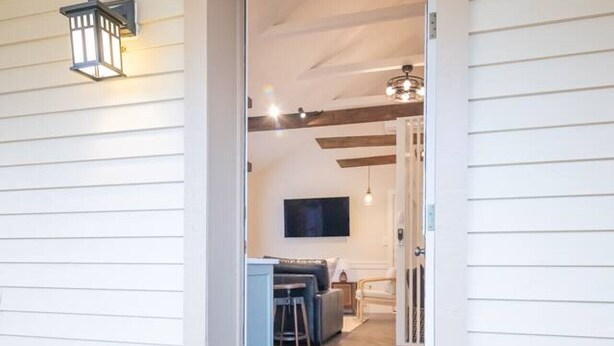 A wooden deck with a doormat, a pair of shoes, and a view into a living area with a TV, sofa, and dining table. - Take your getaway at this magical oasis, central to "everything" (Gordonville)