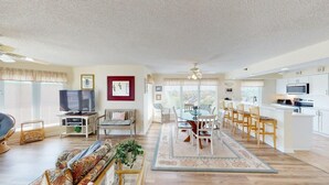 A spacious living room with a dining area, kitchen, and a television.
