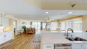 A spacious kitchen with white cabinets, a large island with a sink, and a dining area with a table and chairs.
