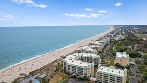 Un hôtel situé sur la côte, composé de plusieurs bâtiments, avec accès à la plage et offrant une vue sur un ciel dégagé.