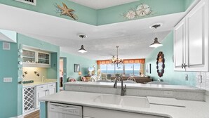 A kitchen with a large island, white cabinets, and a view to the outside.