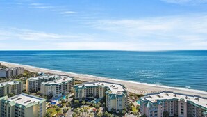 A beachfront hotel with multiple buildings, a pool, and a beach view.