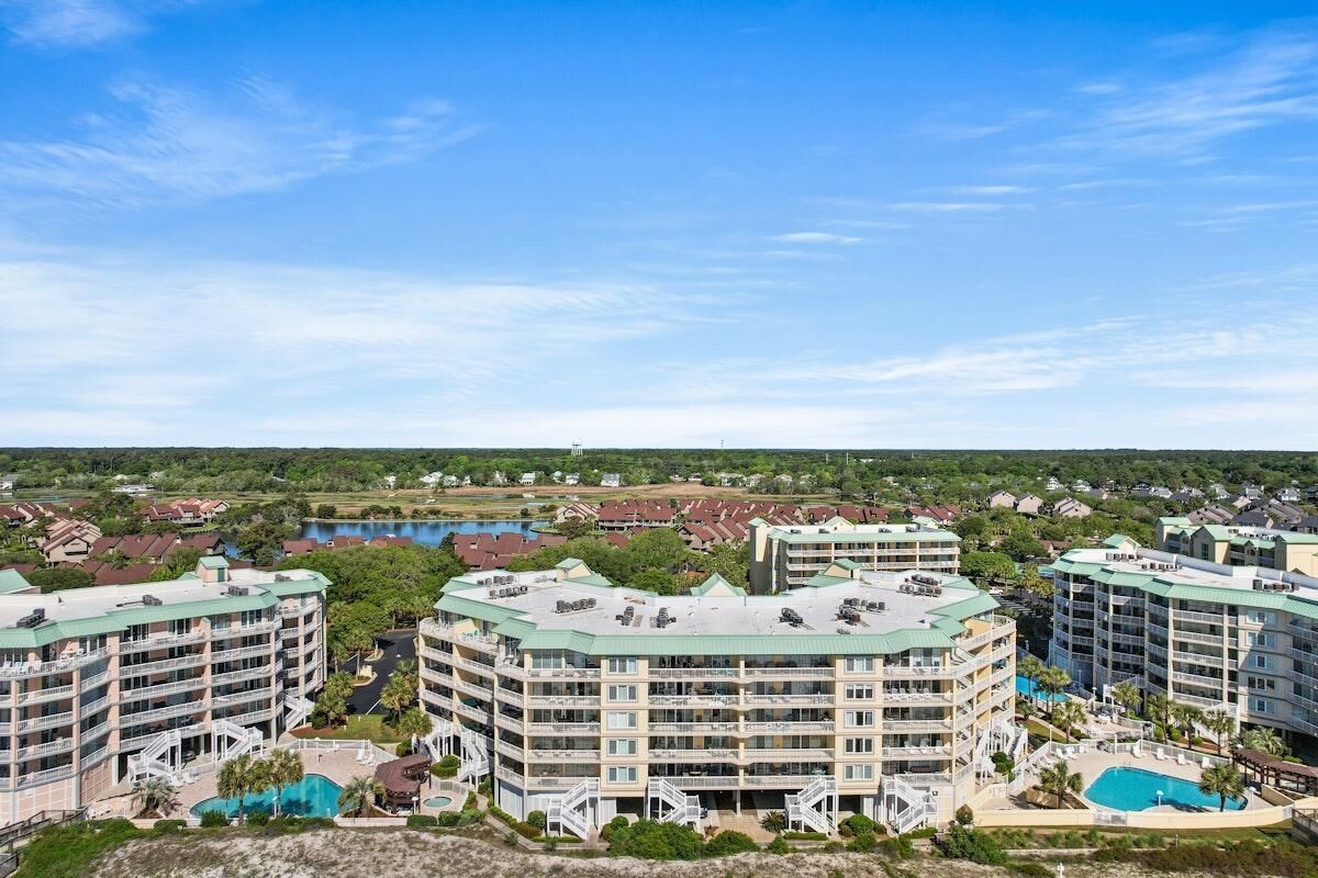 A multi-story hotel with balconies, a swimming pool, and a golf course in the background.