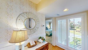 A room with a large mirror, a lamp, and a view through a sliding door. - Lakeside Retreat Spacious 3BR 2BA Resort Amenities (Pawleys Island)