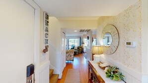 A hallway with a wooden floor, a bench, a wall-mounted mirror, and a decorative wall panel. - Lakeside Retreat Spacious 3BR 2BA Resort Amenities (Pawleys Island)