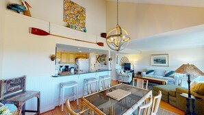 A spacious living area with a glass dining table, wicker chairs, a sofa, and a television. - Lakeside Retreat Spacious 3BR 2BA Resort Amenities (Pawleys Island)