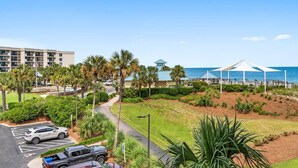 Een resort met een parkeerplaats, palmbomen, een gebouw met een blauw dak en uitzicht op het strand.