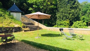 Een gazon met een picknicktafel, een barbecue en een klapstoel.