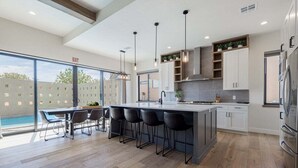 A modern kitchen with a large island, bar stools, and a view of a swimming pool. - Aquarius: Private Pool + Sand Dunes + Golf (Hurricane)