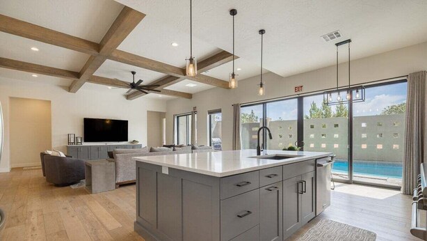 A spacious living area with a large island, grey cabinetry, and a flat-screen TV. - Aquarius: Private Pool + Sand Dunes + Golf (Hurricane)
