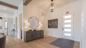 A modern hotel lobby with a wooden floor, a grey console table with a round mirror and lamps, a framed map on the wall, and an exit door. - Aquarius: Private Pool + Sand Dunes + Golf (Hurricane)