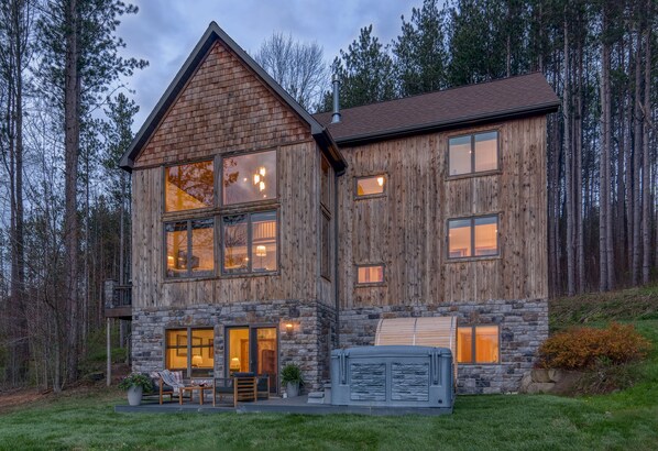 A two-story log cabin with stone accents, large windows, and a stone fireplace.