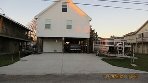 Une maison à deux étages avec un garage, un camion et une remorque pour bateau.