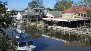 A marina with docked boats, a house with a covered area, and a clear sky. - Bayou Living (Barataria)
