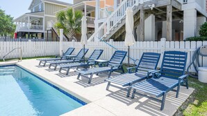 A swimming pool with blue lounge chairs and a white fence.