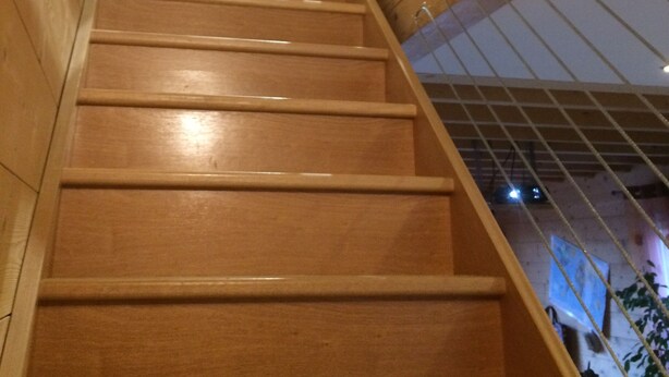 A wooden staircase with a white railing, leading upwards.