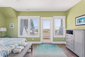 Un dormitorio con cama, mesita de noche, cómoda y ventana con vista a la playa.