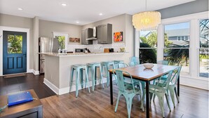 A modern kitchen with a central island, grey cabinets, and a large window offering a view of the outdoors.