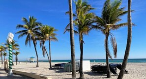 A beach with palm trees, a bike path, and a lifeguard tower.