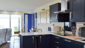 A modern kitchen with dark blue cabinets, a white countertop, and a microwave.