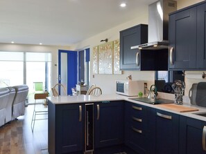 A modern kitchen with dark blue cabinets, a white countertop, and a microwave. - 2 bedroom accommodation in Connel, near Oban (Connel, near Oban)