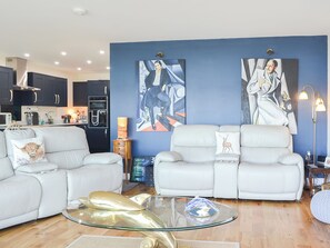 A modern living room with two white leather sofas, a glass coffee table, and artwork on the walls. - 2 bedroom accommodation in Connel, near Oban (Connel, near Oban)