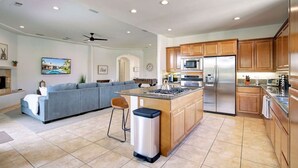 A modern kitchen with a central island, stainless steel appliances, and wooden cabinets.