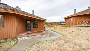 Eine Holzhütte mit Veranda, Kiesweg und einem trockenen, saftigen Feld.
