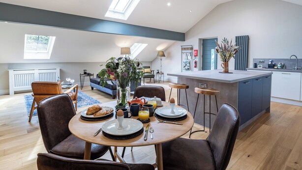 Un loft spacieux comprenant un coin repas, une cuisine et une grande verrière.