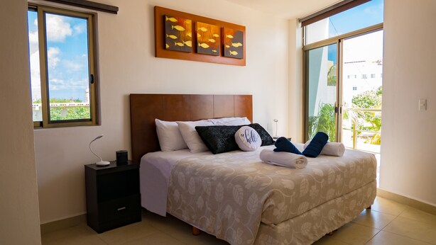 A bedroom with a bed, nightstand, and artwork on the wall. - Suite isla Mujeres (Isla Mujeres)
