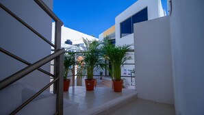 A narrow outdoor corridor with potted plants, a metal railing, and a staircase leading to a higher level. - Suite isla Mujeres (Isla Mujeres)
