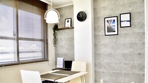 A modern office space with a white table, two white chairs, a black clock, and framed pictures on the wall. - Panoramic Ocean View - downtown/ high speed WiF (Ishigaki)