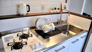 A compact kitchen with a gas stove, a sink, and a dish drying rack. - Panoramic Ocean View - downtown/ high speed WiF (Ishigaki)