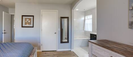 A bedroom with a bed, a dresser, a mirror, and a door.